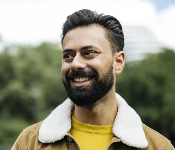 Candid portrait of early 30s man smiling and standing outdoors
