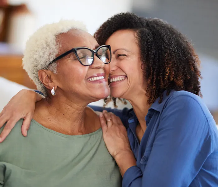 senior woman and her adult daughter embracing affectionately and smiling