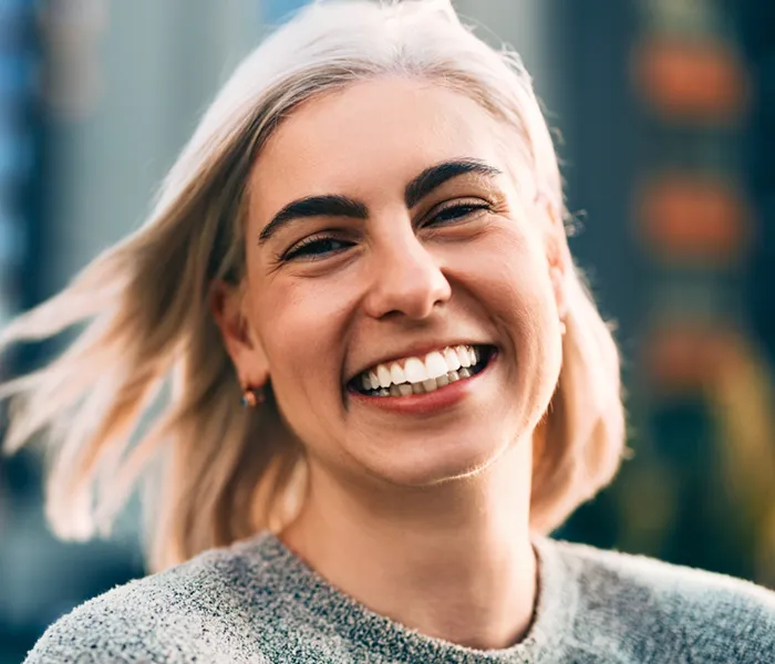 happy woman outdoors, smiling brightly with background blur